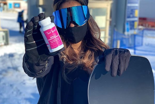 woman skiing holding supplement bottle