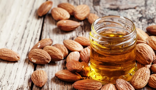 jar of almond oil surrounded by almonds