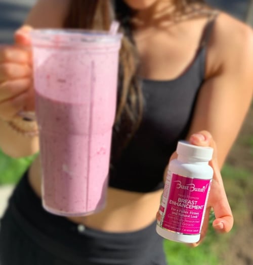 woman holding a pink smoothie and Bust Bunny’s breast enhancement supplements