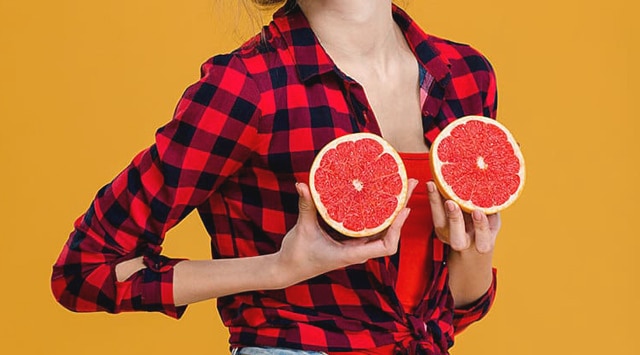 young girl holding orange halves against her chest