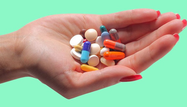 woman holding different pills
